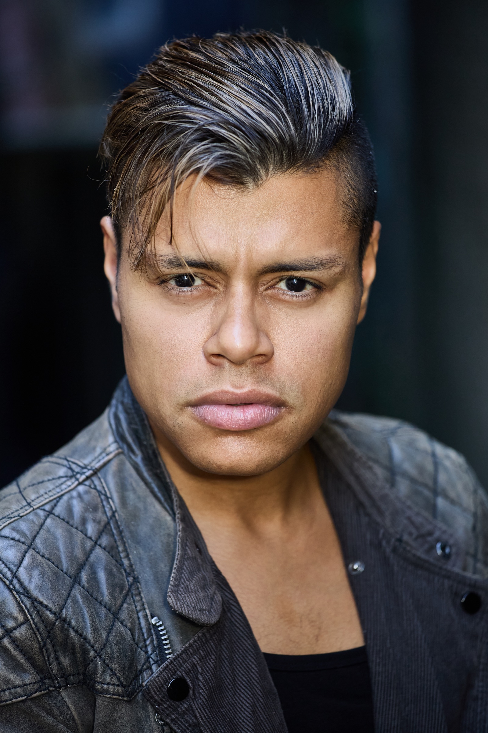 Aaron Stier in a dramatic theatrical headshot wearing a dark jacket